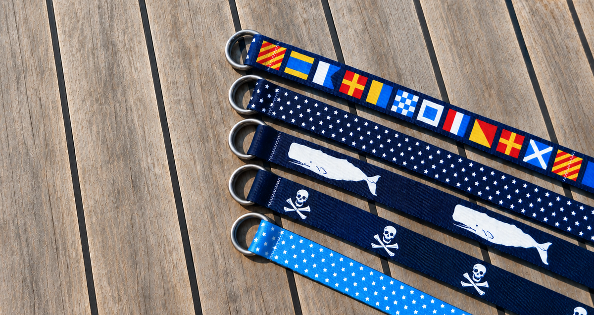 Nautical belts in signal flag, whale, Jolly Roger and star designs on teak boat deck